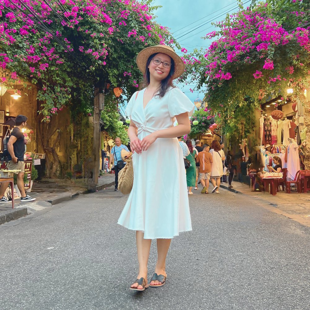 Thu, Gründerin von Bloom & Shine, im weißen Kleid mit Sonnenhut.
